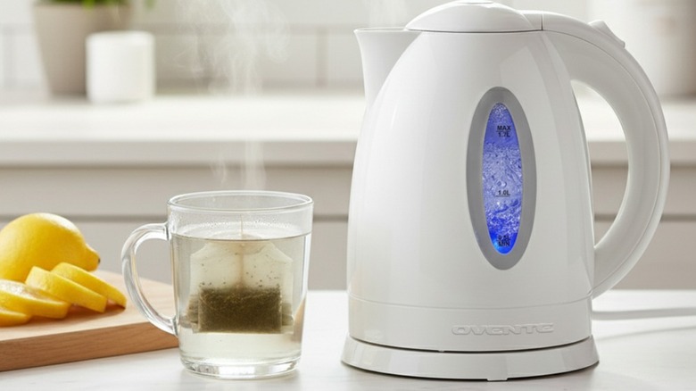 A white electric kettle beside a cup of tea