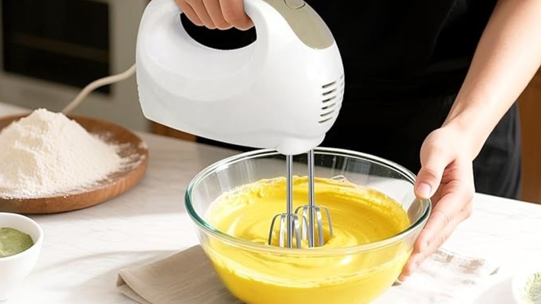 Hand mixing a yellow mixture with a hand mixer
