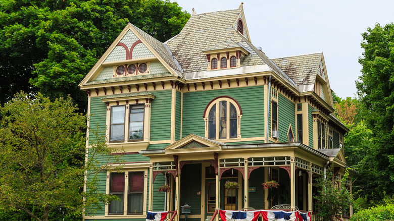 A Victorian home with green siding and butter yellow trim