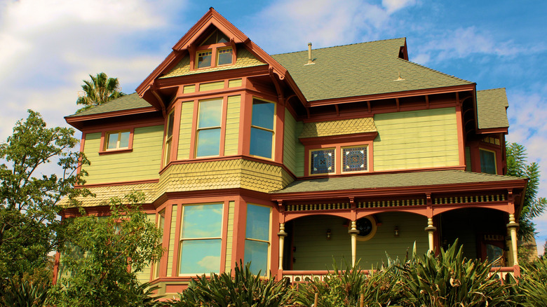 A Victorian home in lime green with olive green roofing and burnt orange trim