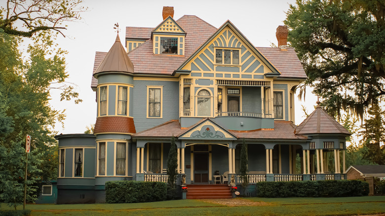 A large Queen Anne style Victorian home in powder blue with butter yellow trim