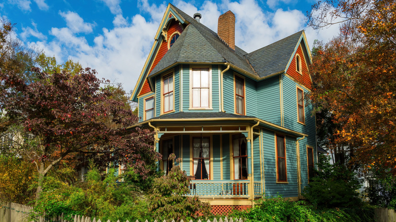 A Victorian home with a teal, brick red, and mustard accents
