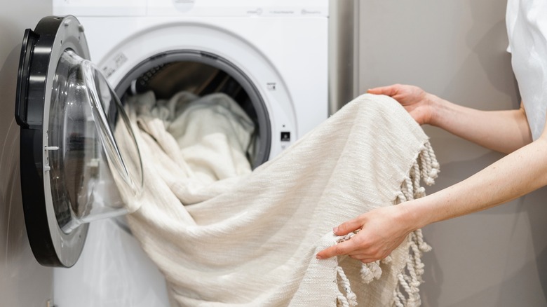 person holding blanket at washing machine