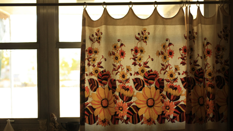 Floral cafe curtain hanging from a kitchen window