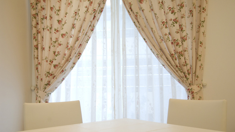 Pleated floral curtains hanging on either side of a dining room window