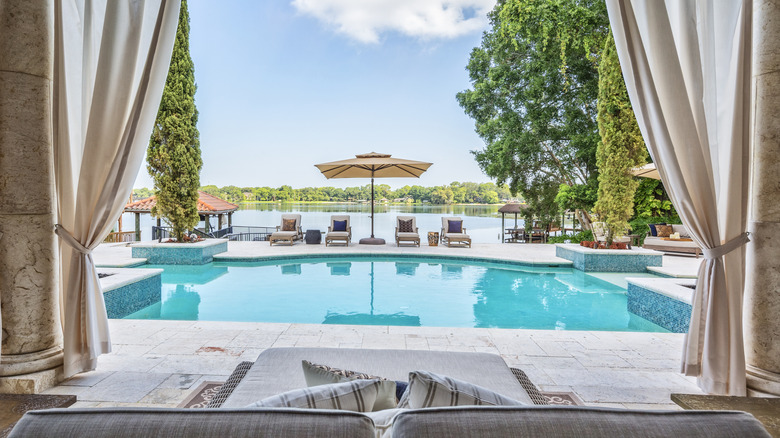 Canvas tie-back curtains framing a pool, viewed from a stone terrace