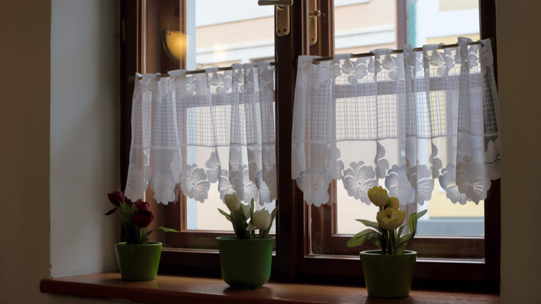 Woman opening sheer curtains in living room