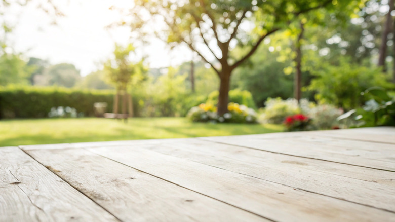Wood floor of a deck with backyard in background.