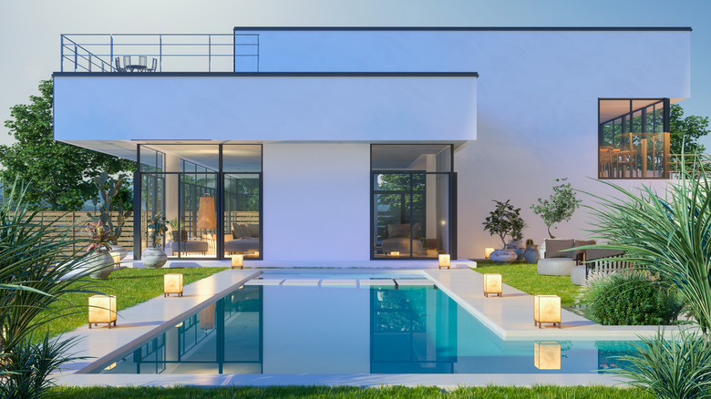 A large backyard swimming pool with modern home in background