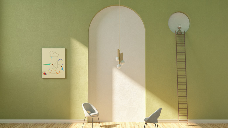 A room with avocado green walls, wall ladder and two minimalistic chairs.