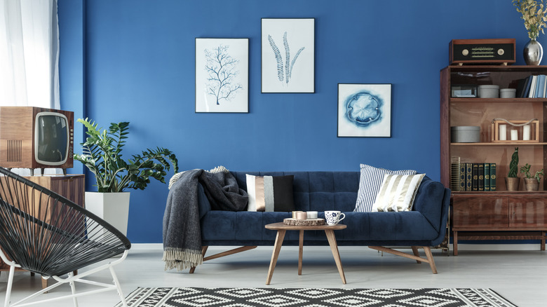 A warm blue wall with a retro tv, blue sofa and bookcase.