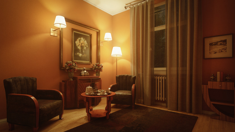 A living room with classic 70s armchairs and three lights arranged around a painting.