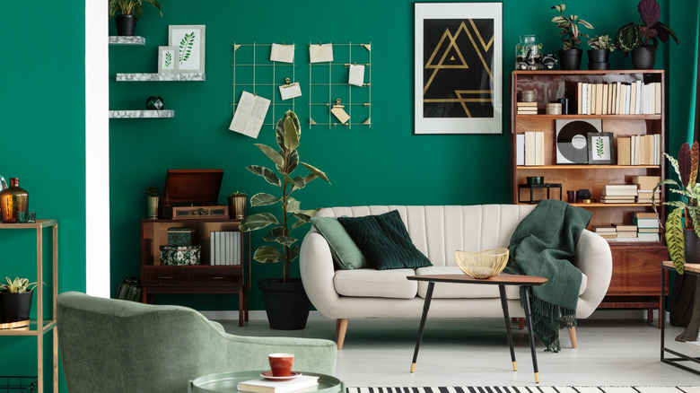 An emerald green living room with cream sofa and green throws.