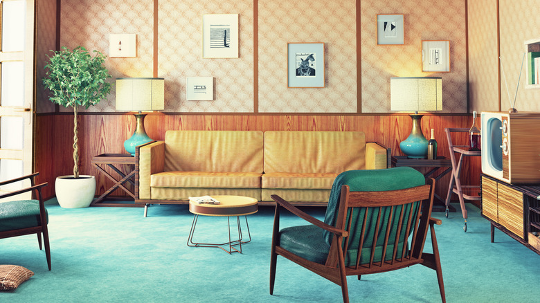 A 1960s living room with teal carpet and an orange couch.