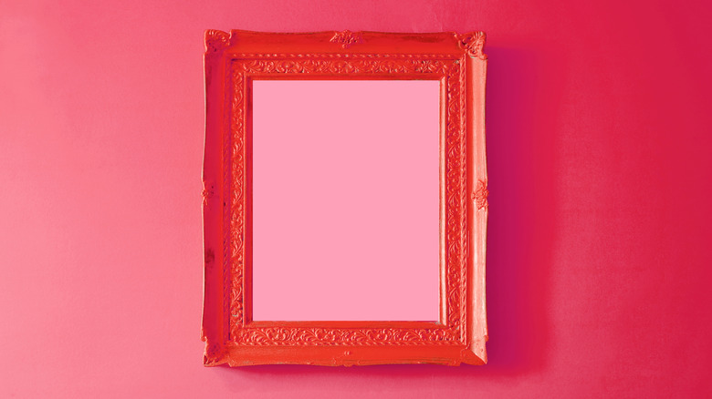 A raspberry painted wall with a red photo frame in the centre.