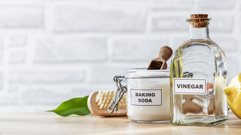 a jar of baking soda and vinegar on counter with brush and lemon