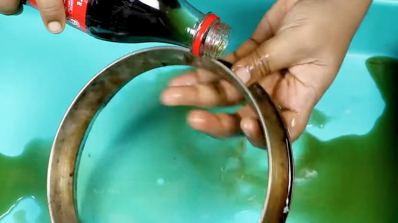 someone rubbing coke on stainless steel cooking rim