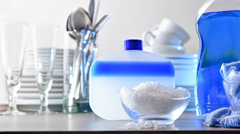 salt next to cleaning supplies, glasses, plates, cups, and silverware