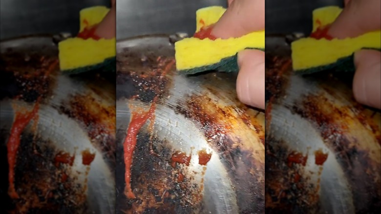 someone with a sponge wiping tomato paste on pot