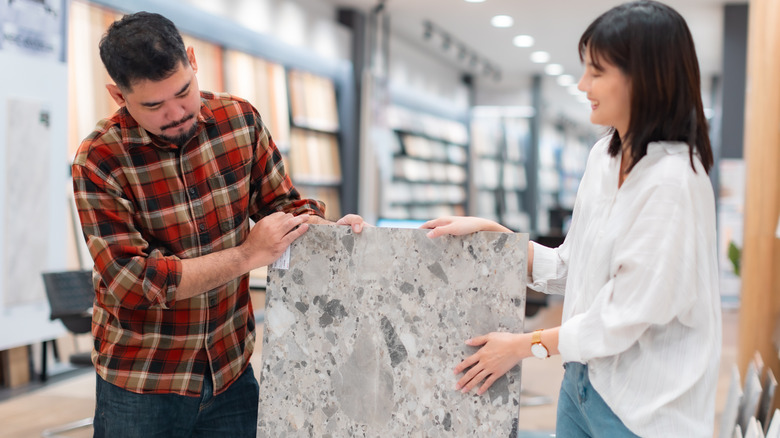 A couple inspecting a paving slab in a retail setting