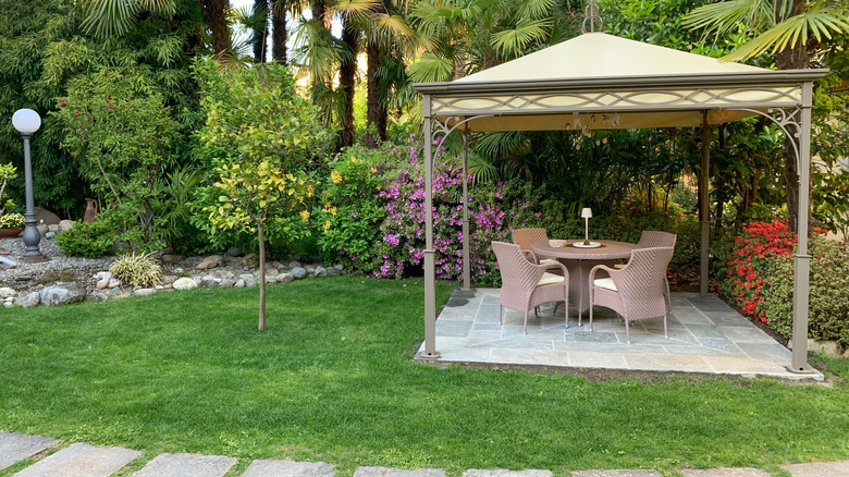 A patio with gazebo cover in the middle of a garden