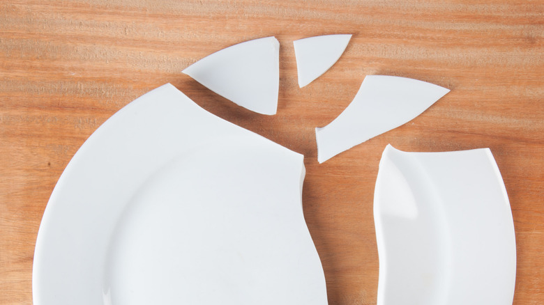 a broken white plate on a wooden surface