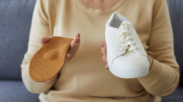 a woman holding an insole and a shoe in each hand