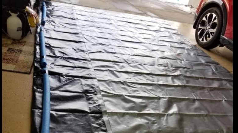 Tarp with pool noodles placed in the bottom of a garage