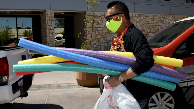 Man carrying a variety of pool noodles