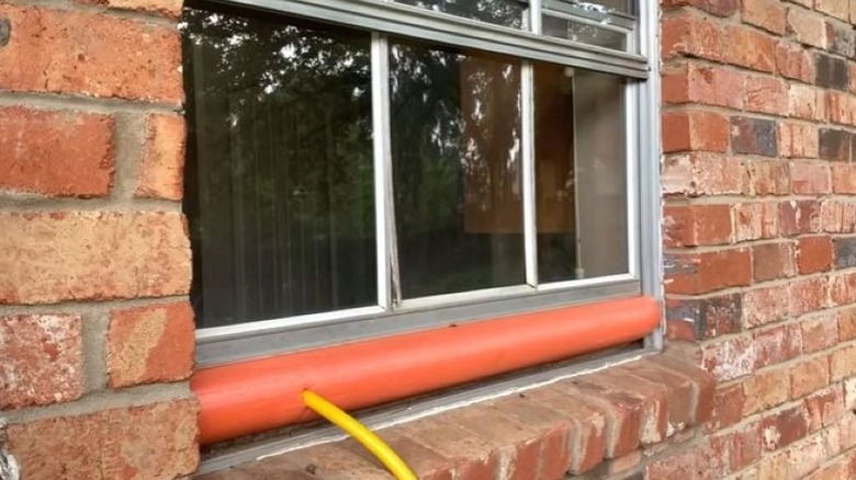 Window with pool noodle and an extension cord running through it