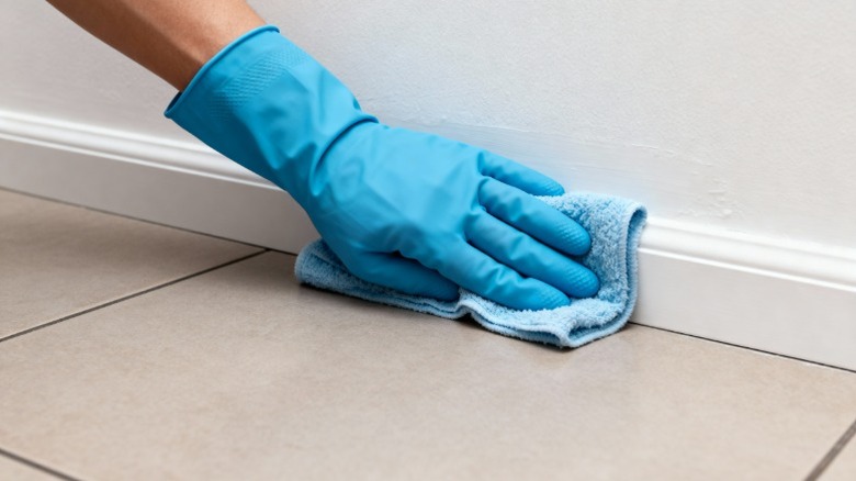 Person wiping down a baseboard