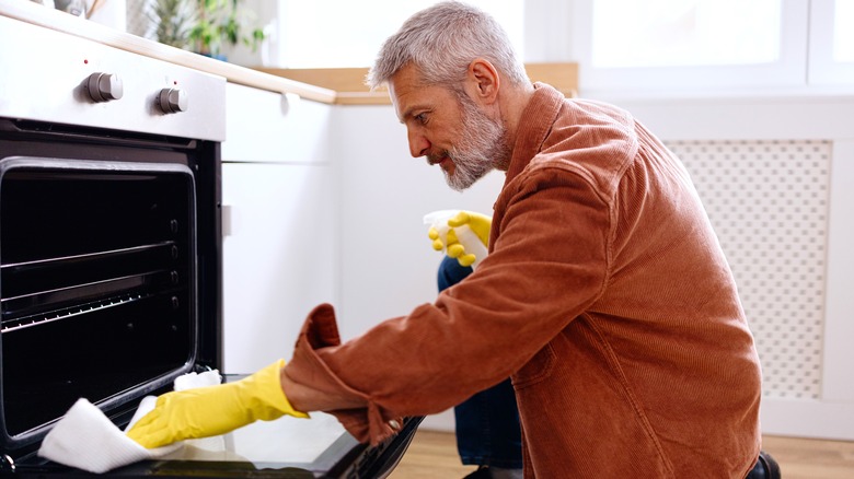 A man cleans out an oven.