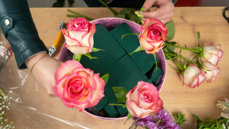 Floral foam sitting on a table with faux flowers inserted into it.