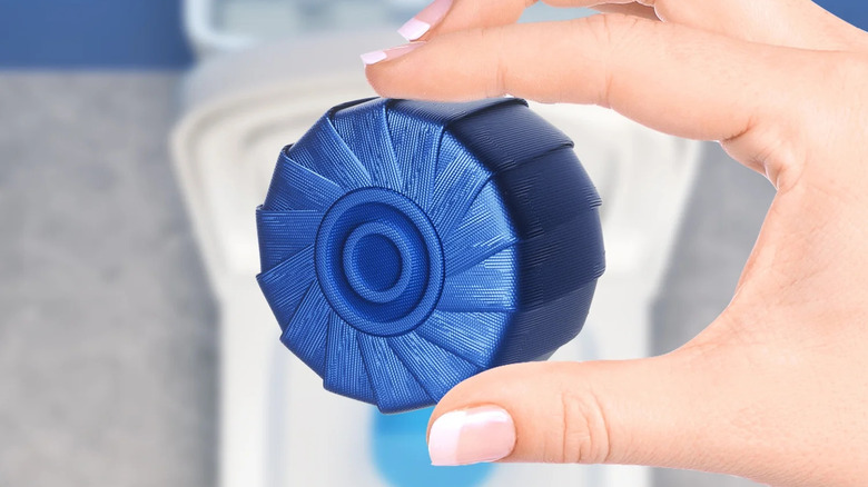 A person holding a toilet bowl cleaner tablet