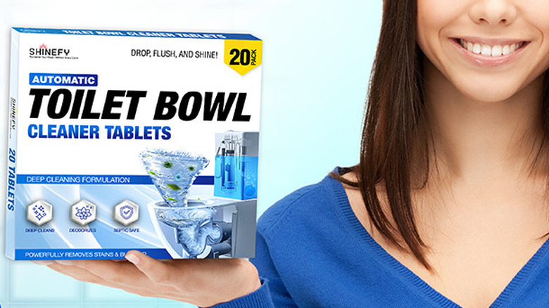 A woman holding a box of Shinefy toilet bowl cleaner tablets