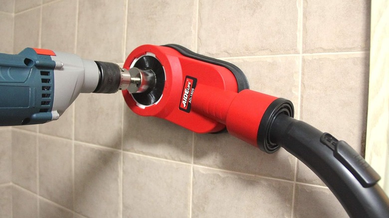 A person using a dust collector when drilling into tile