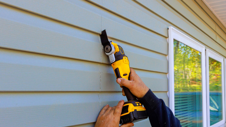 A person cutting siding with a multi tool