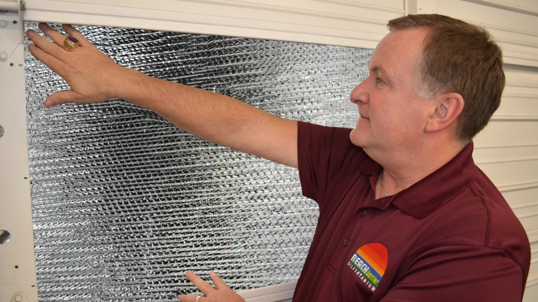 Man installing Reach Barrier 3009 Garage Door Insulation Kit on garage door