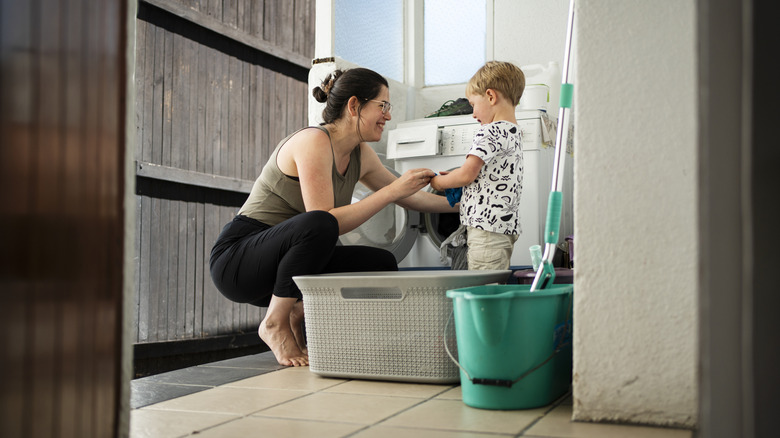 Mother and son in family household next to a washing machine