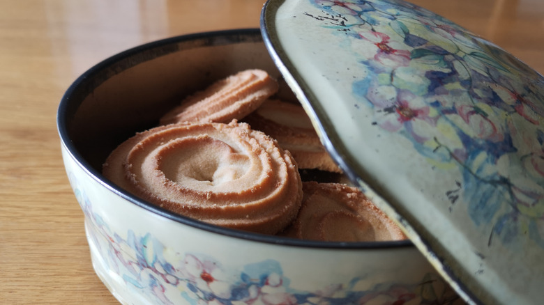 open vintage blue cookie tin with cookies in them on a table