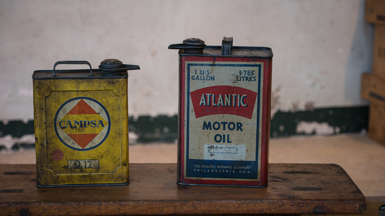 two dirty vintage motor oil tins sitting on bench