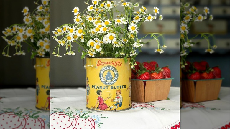 vintage yellow peanut butter in holding white flowers next to strawberries