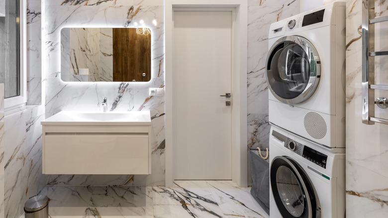 A stacked washer and dryer in a marble bathroom