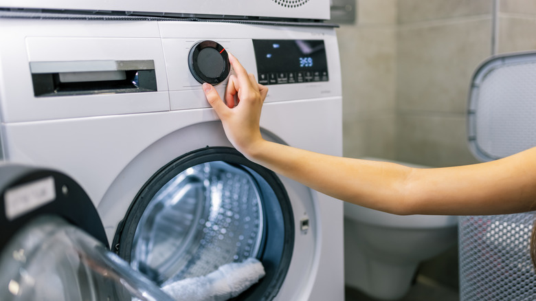 A hand pushing buttons on a washing machine