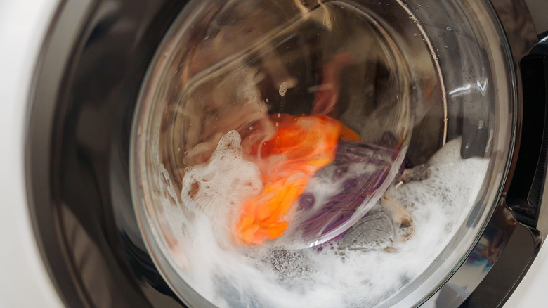 Closeup of the clear door of a front-load machine as it's washing clothes