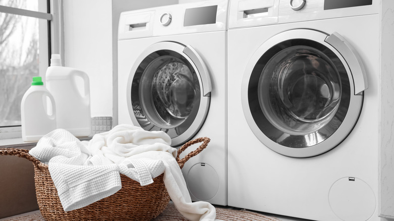 A basket of laundry next to a washer and dryer