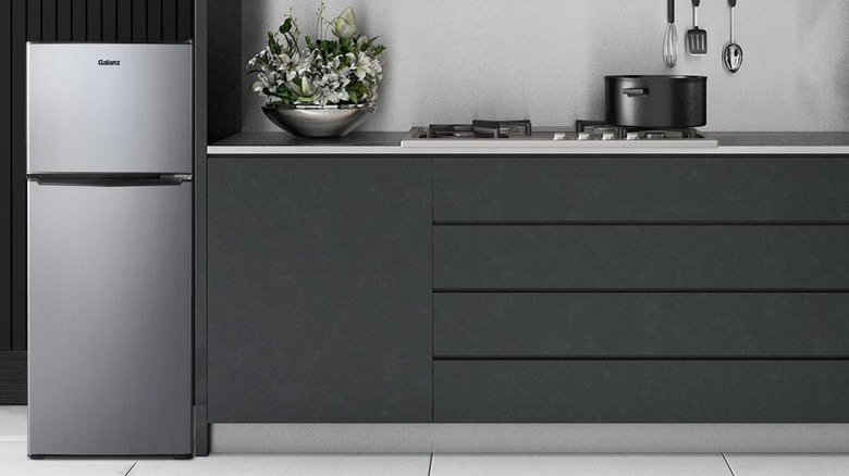 A compact stainless steel fridge on one end of a kitchen