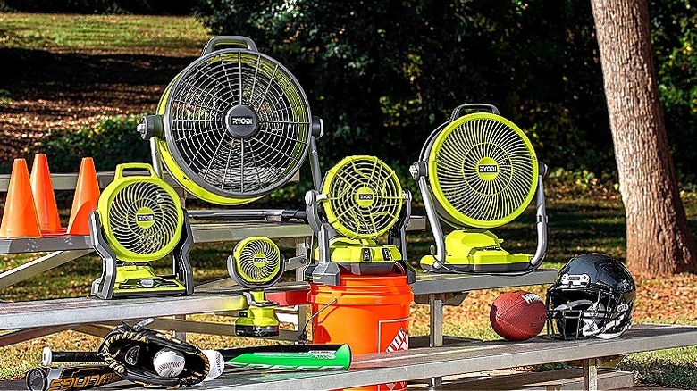 A group of Ryobi mister fans on a four-tier bench in a park with sports equipment on the lower level