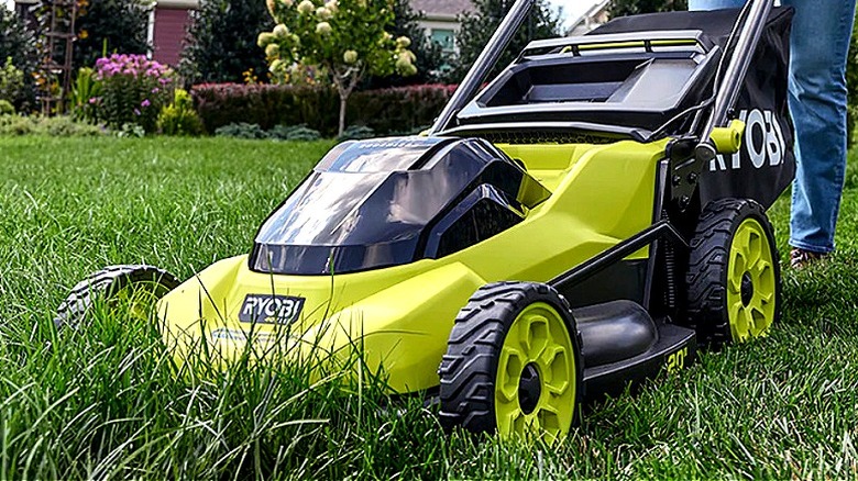 A close-up of a person pushing a mower through tall grass