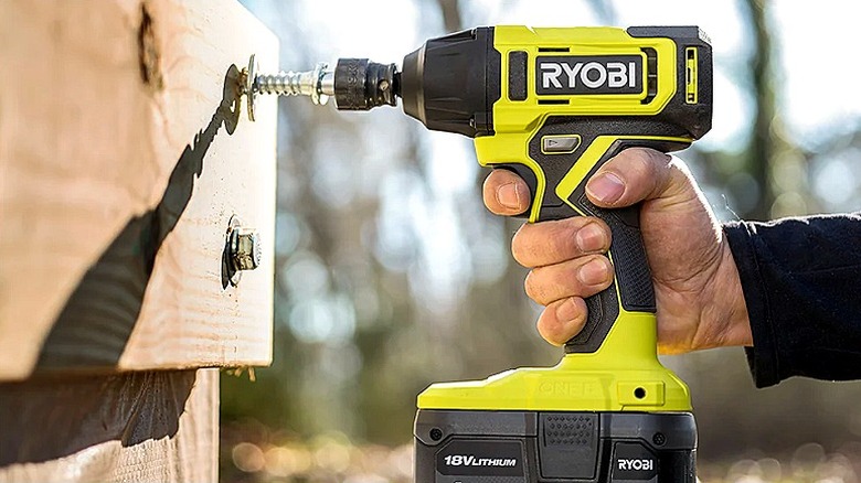 A person using an impact wrench to screw in large bolts